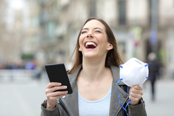 podekscytowana kobieta trzymajaca telefon i maske