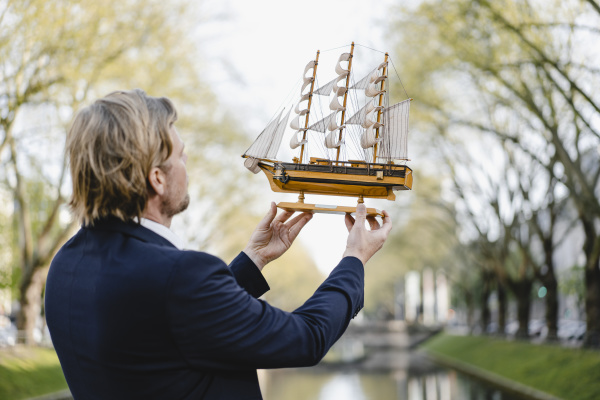 biznesmen trzymajacy model statku w kanale