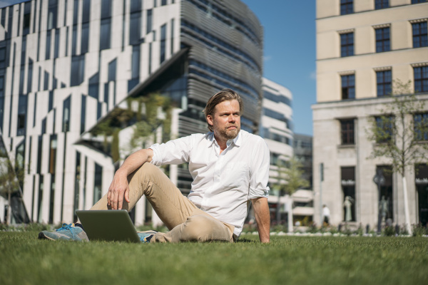 biznesmen z laptopem siedzacym w trawie
