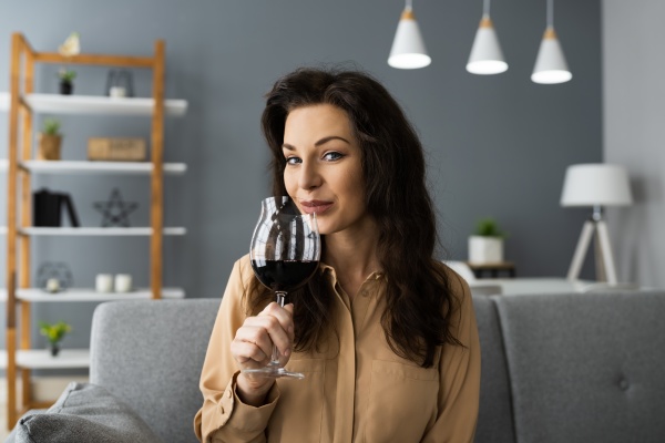 kobieta pijaca czerwone wino w wideokonferencji