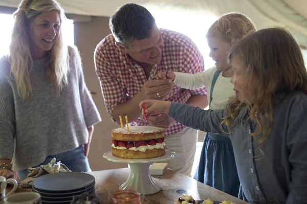 rodzina swietujaca urodziny z tortem truskawkowym